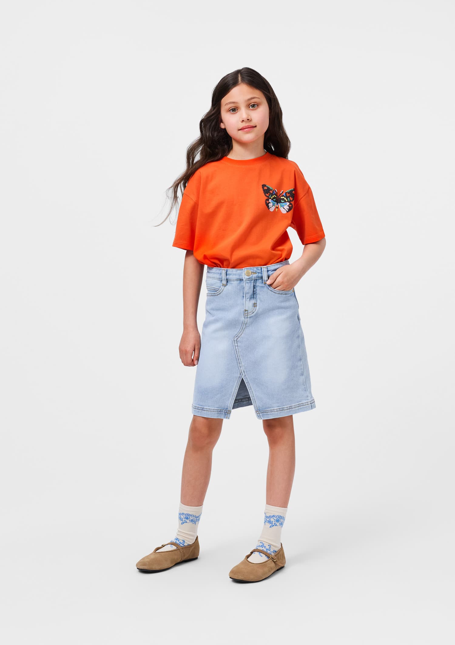 Young girl wearing an orange t-shirt with a butterfly design