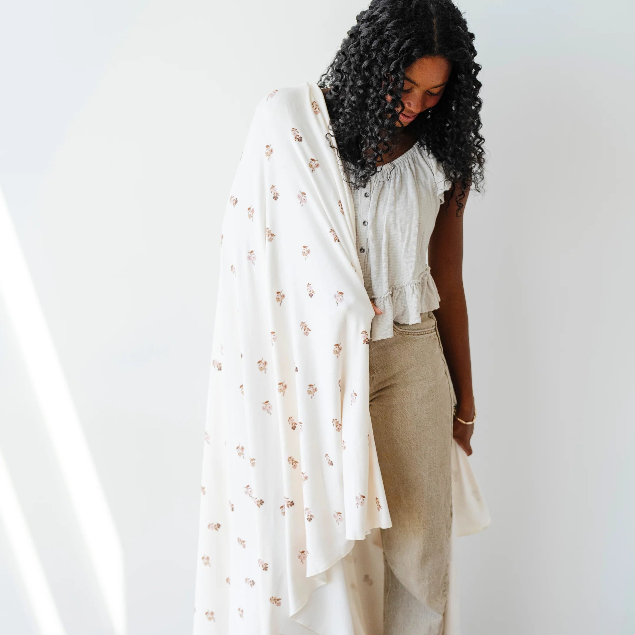 Woman holding a white floral stretch swaddle blanket