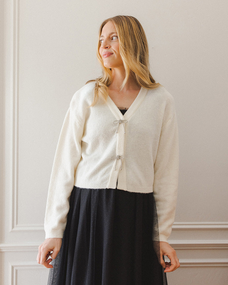 Ivory cardigan with bow details on the front.