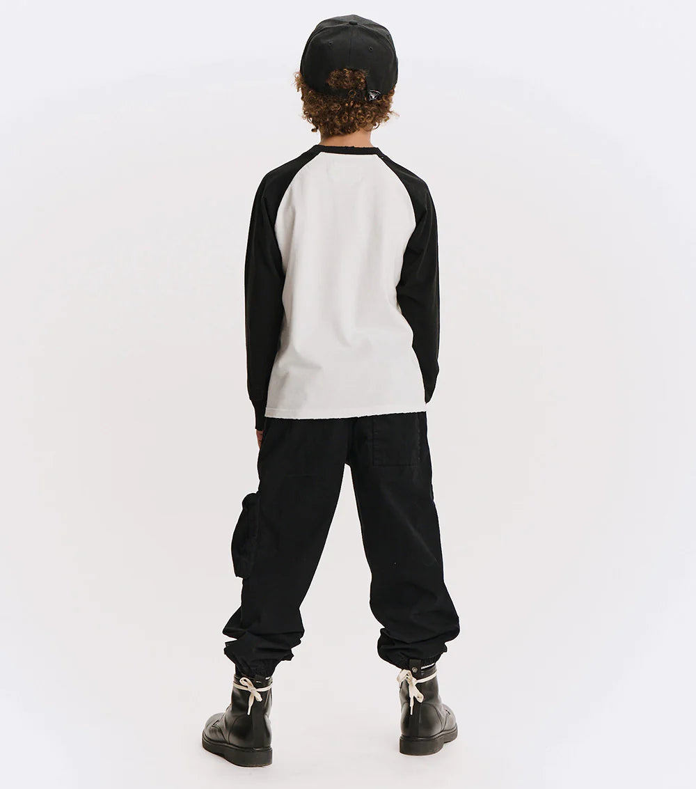 Person wearing a black and white long-sleeve shirt with black pants on a white background