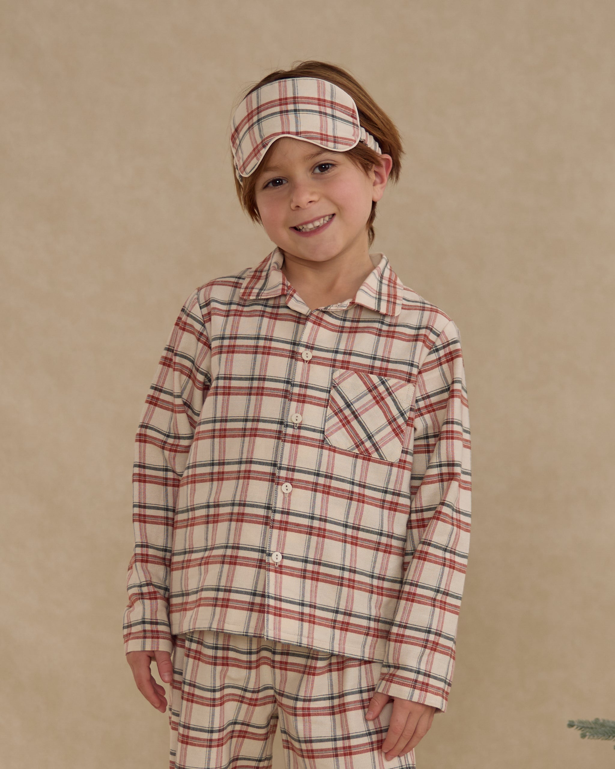child wearing a matching plaid two-piece set against a beige background