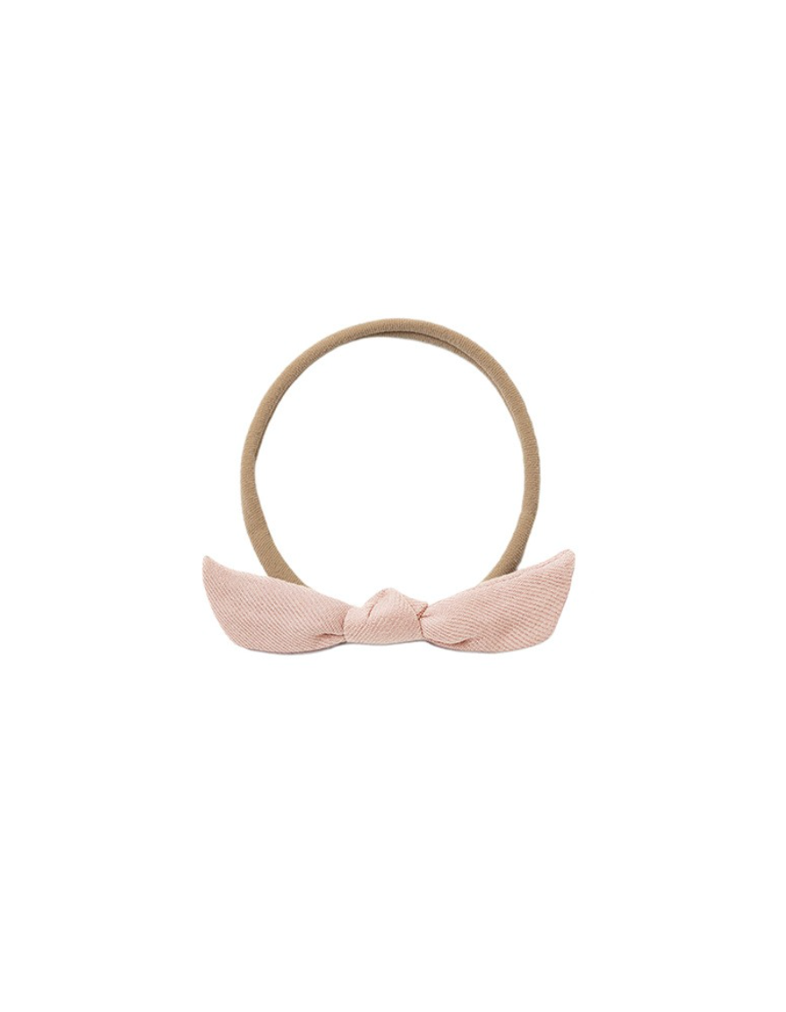 A light pink fabric bow headband with a tan elastic band, shown against a plain white background.