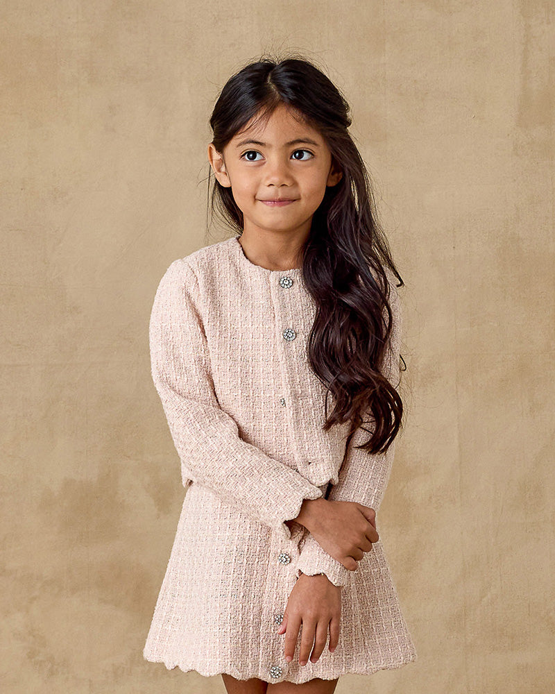 Young girl wearing a light pink dress against a beige background