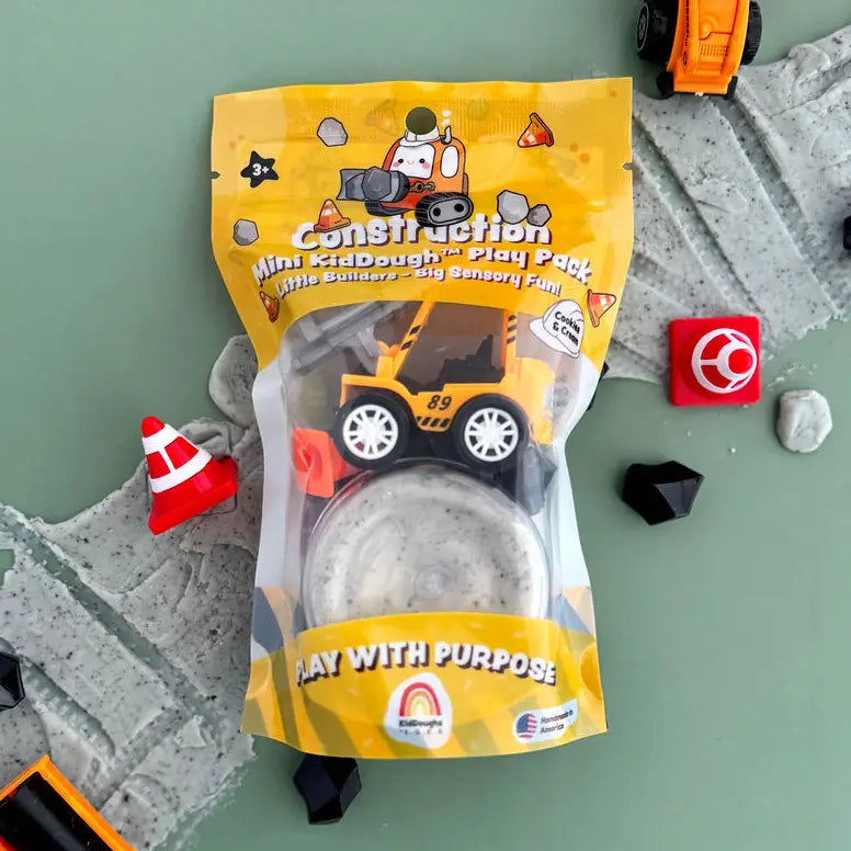 Construction-themed play dough pack with toy truck and accessories on a green surface