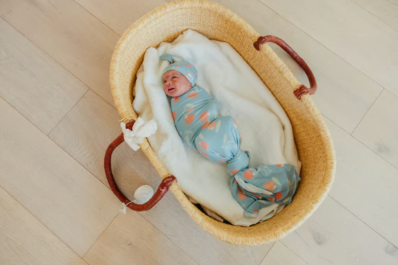 baby swaddled in clementine swaddle blanket with matching hat