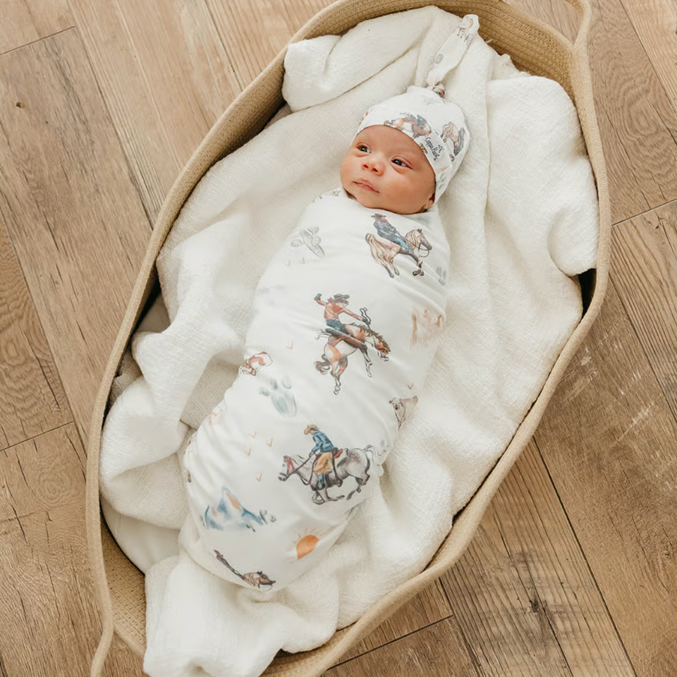 baby swaddled in cowboy print swaddle with matching hat