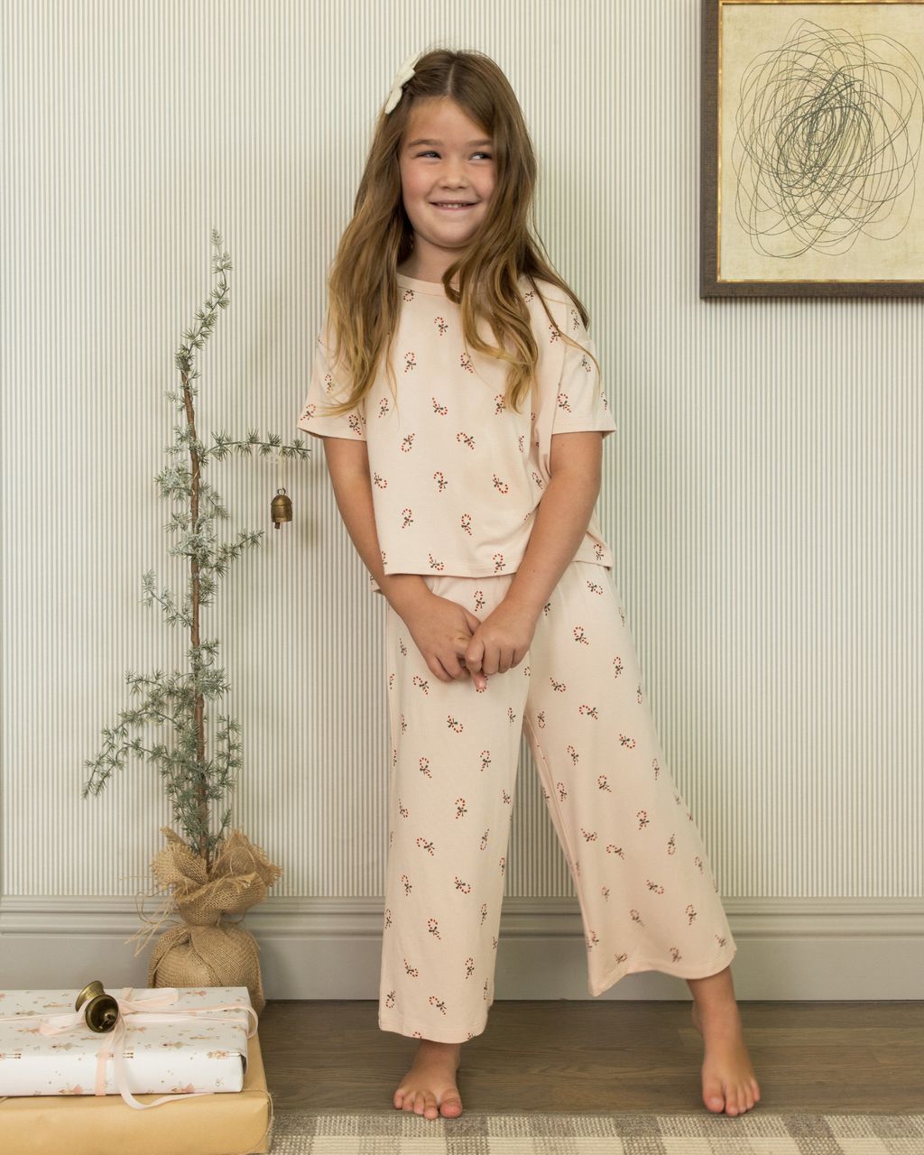 Young girl wearing a matching holiday set with candy cane details.