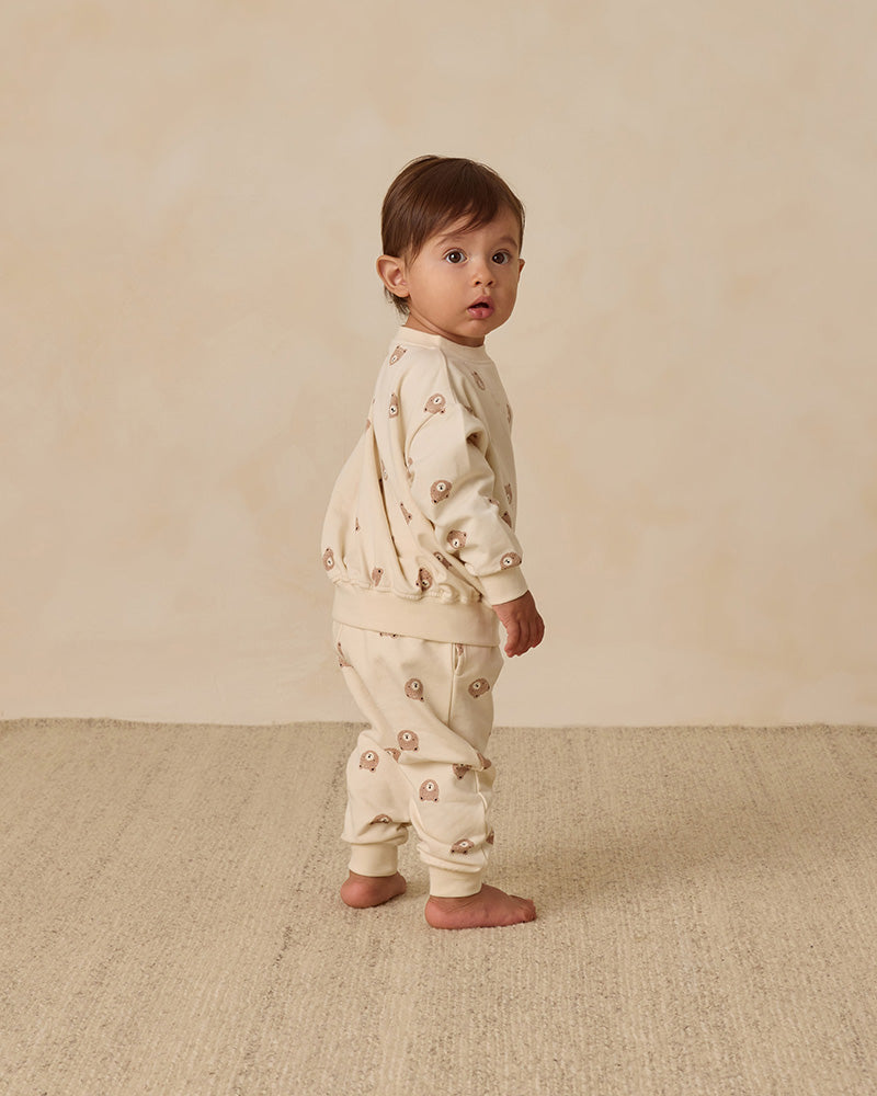 Baby wearing a cream-colored outfit with small bear patterns standing