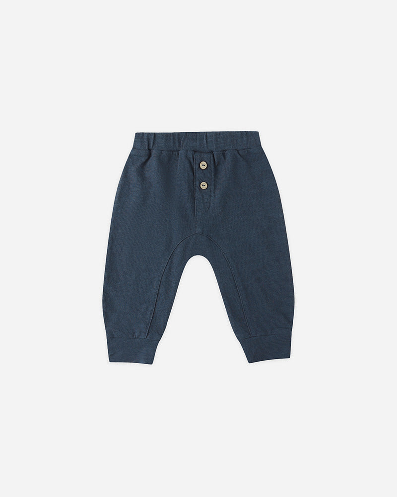 Navy blue baby pants with button details on a light gray background
