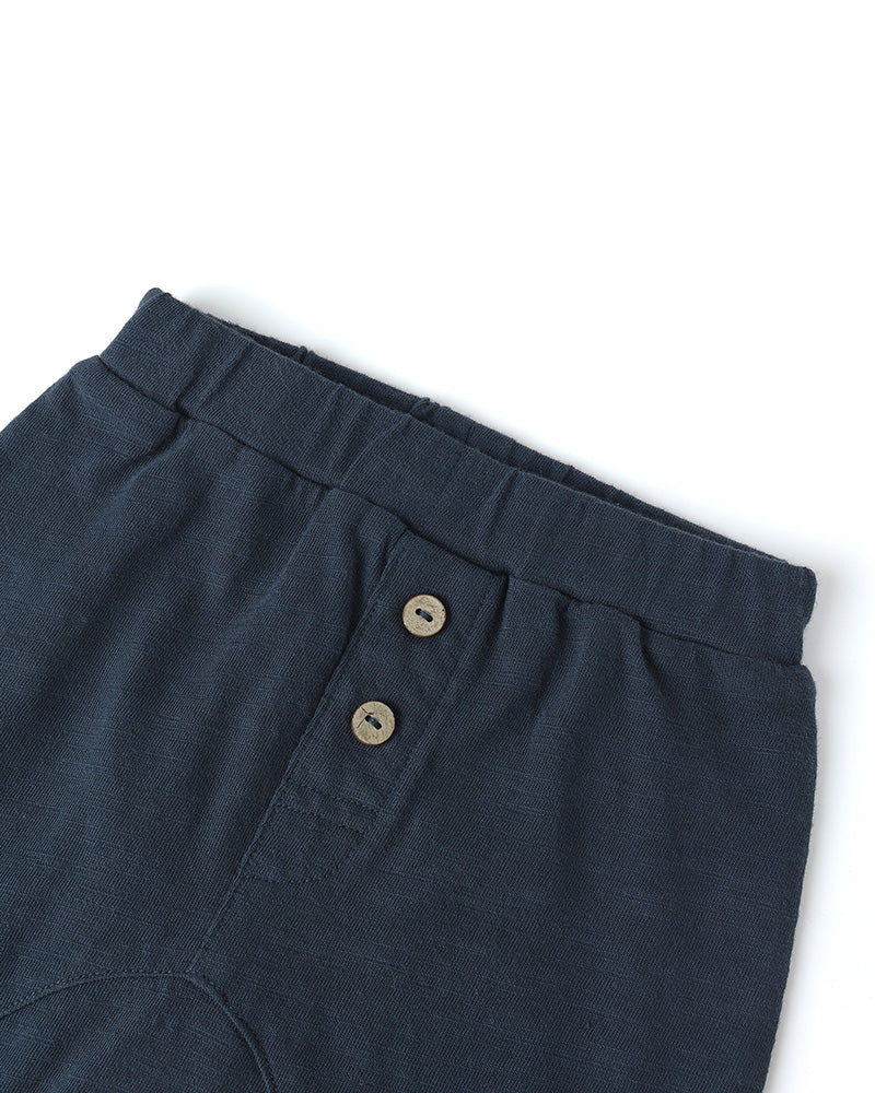 Navy blue pants with button details on a white background