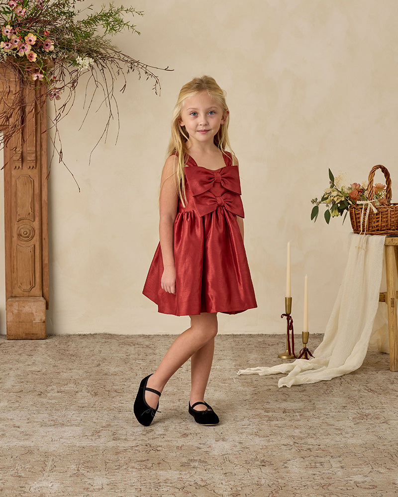 Young girl in a red dress with two bows on the front