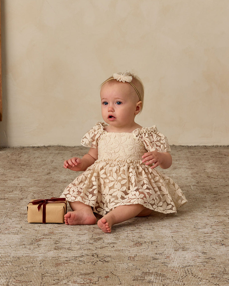 Baby in cream floral dress with ruffle details