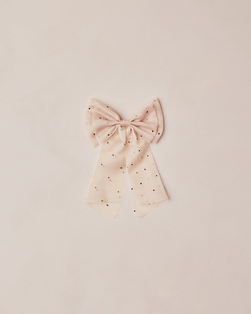 Pink bow with black polka dots on a light pink background