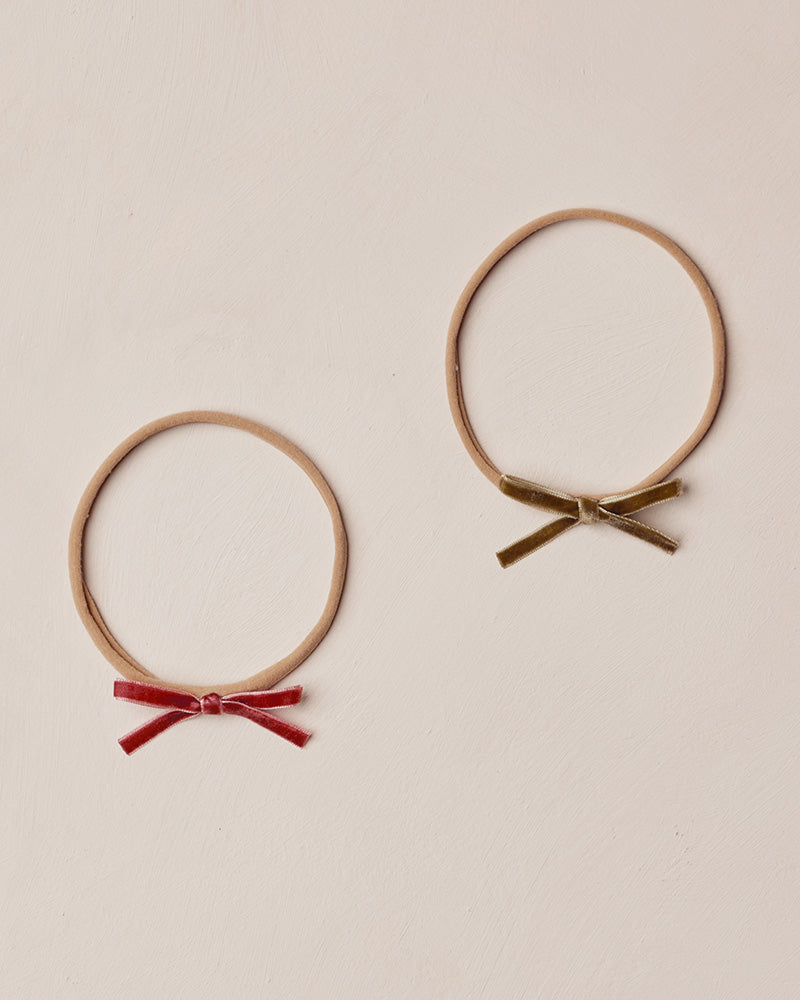 Two headbands with red and gold bows on a beige background