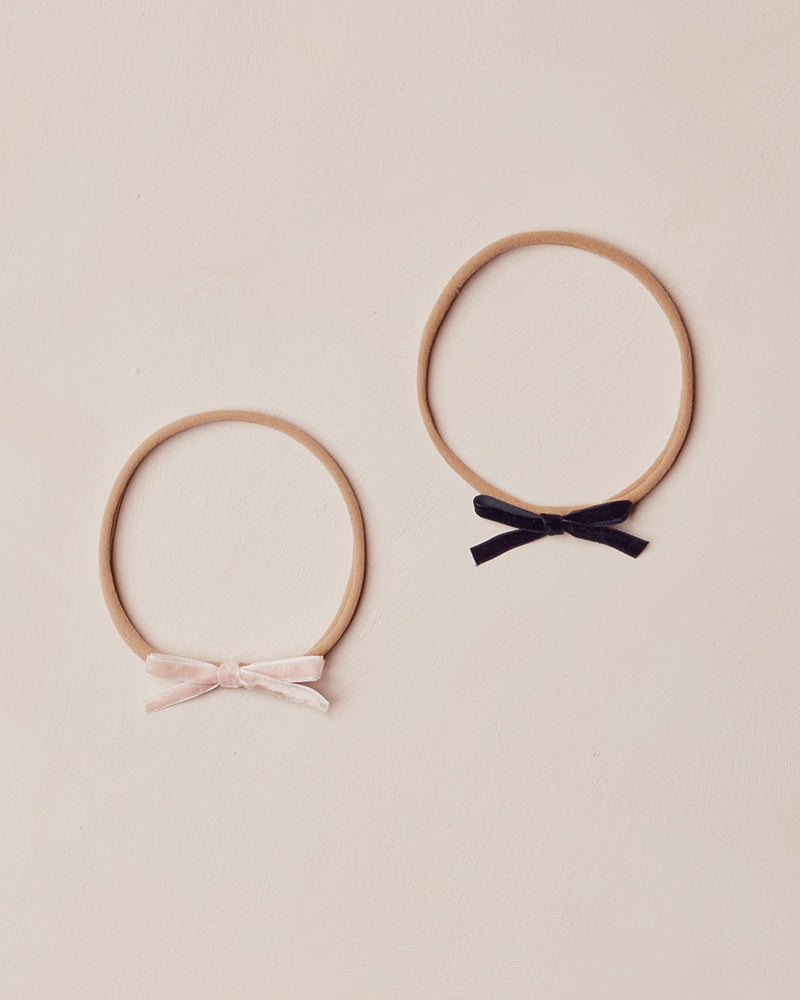 Two headbands with fabric bows on a beige background
