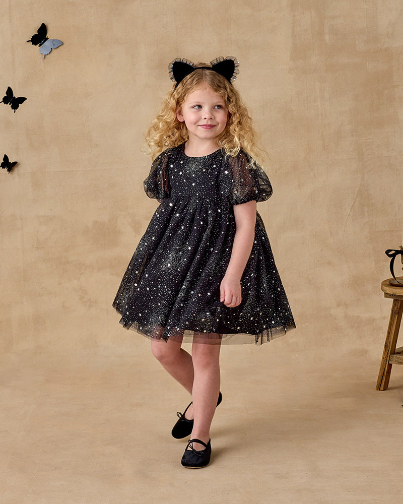 Young girl in a black star glitter tulle dress with a puffy sleeve