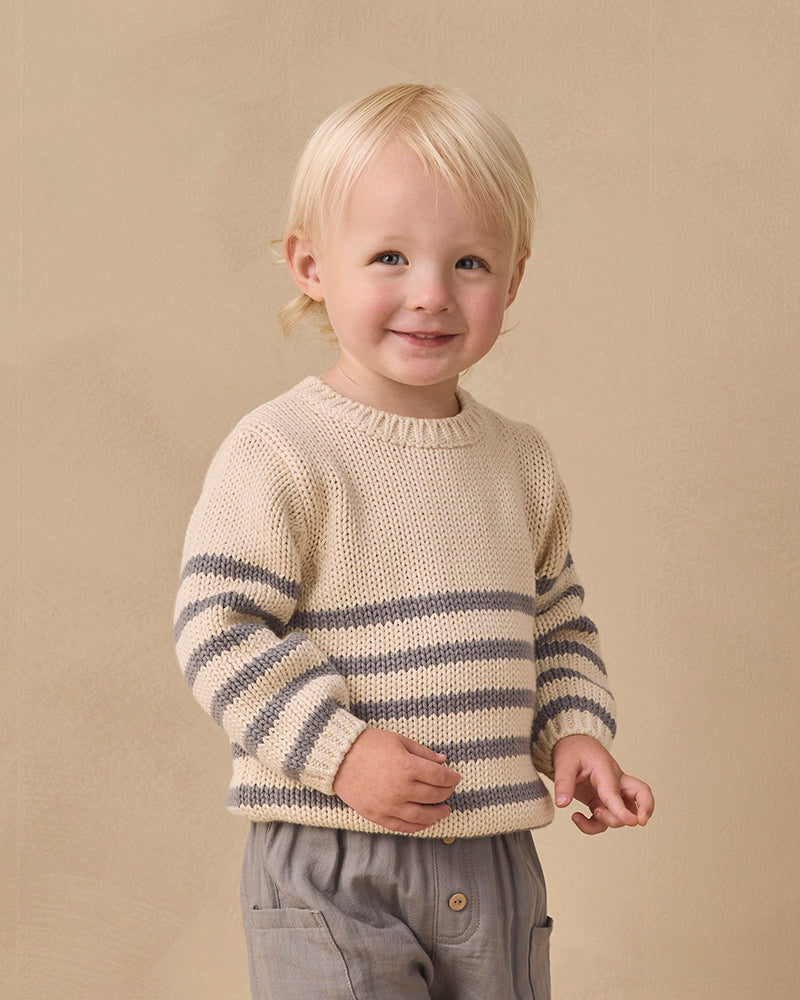 A cream-colored knit sweater with horizontal gray stripes across the lower half and sleeves, featuring a three-button henley neckline, shown against a plain white background.