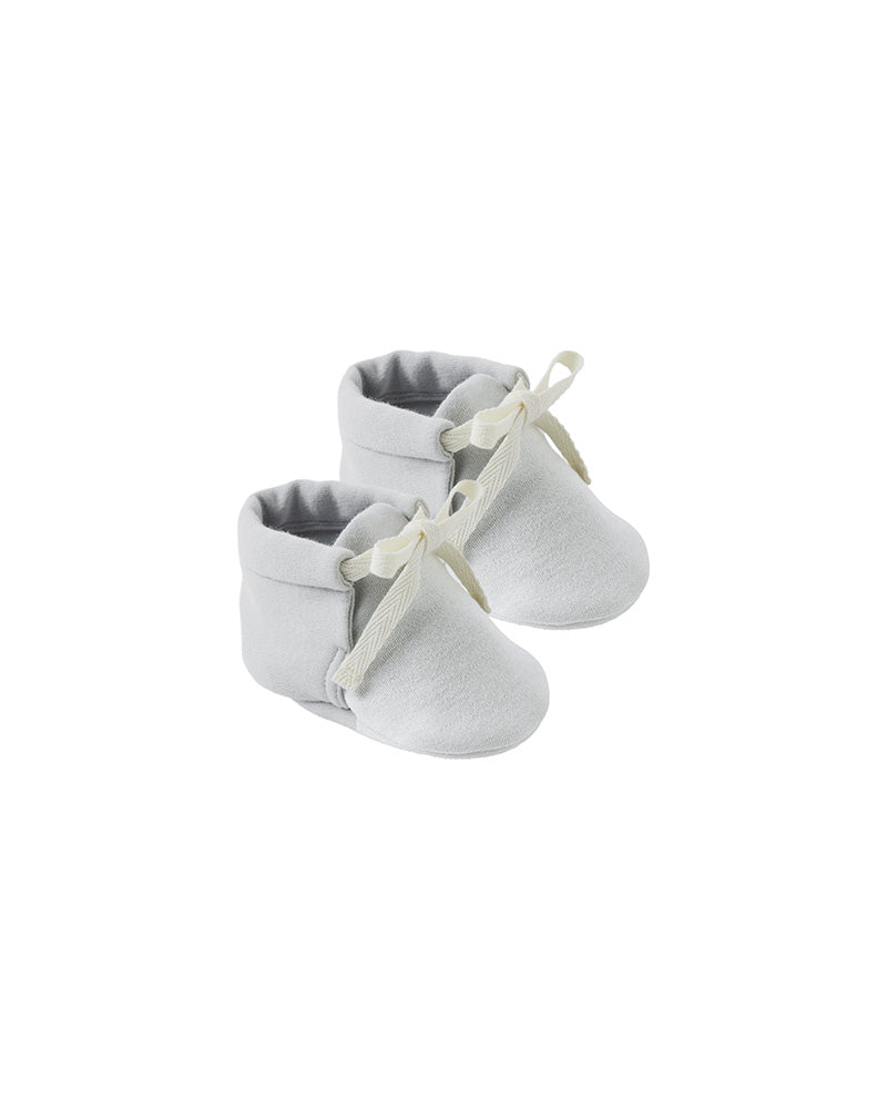 Pair of light blue baby booties with white laces on a white background