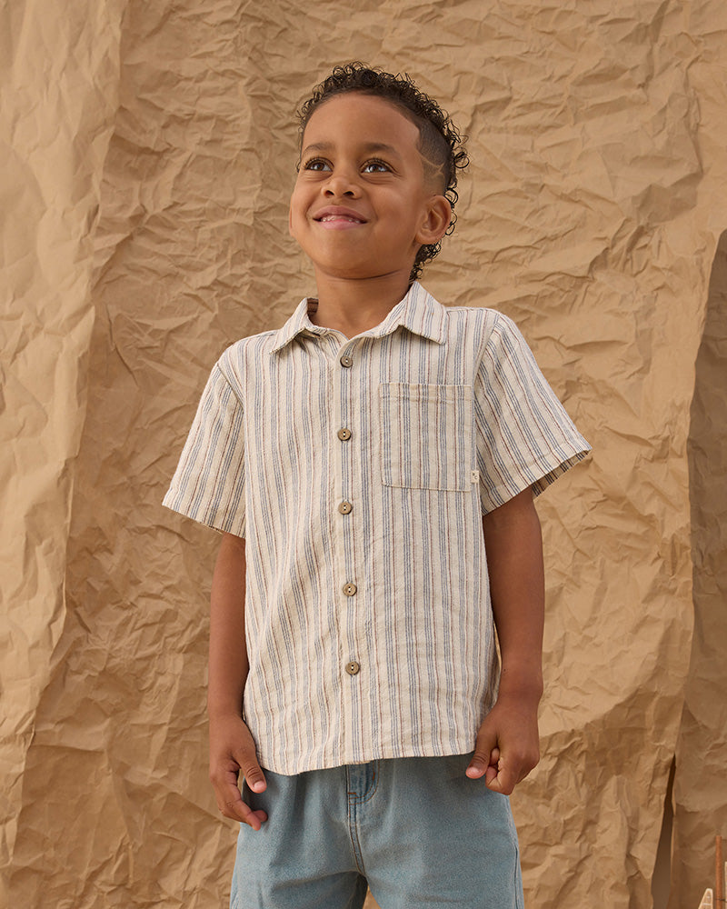 Child wearing a striped button up shirt against a textured brown background