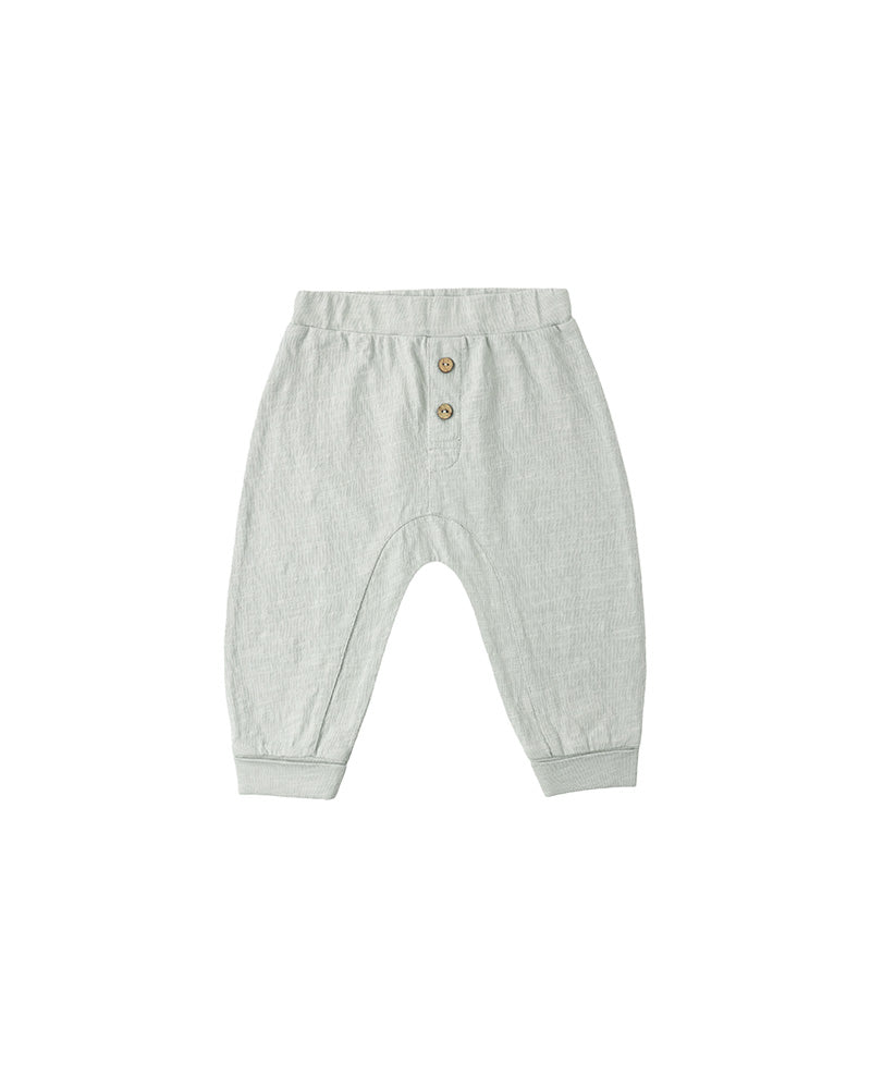 Light blue/green baby pants with button details on a white background