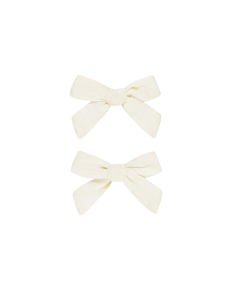 Two cream-colored hair bows on a white background