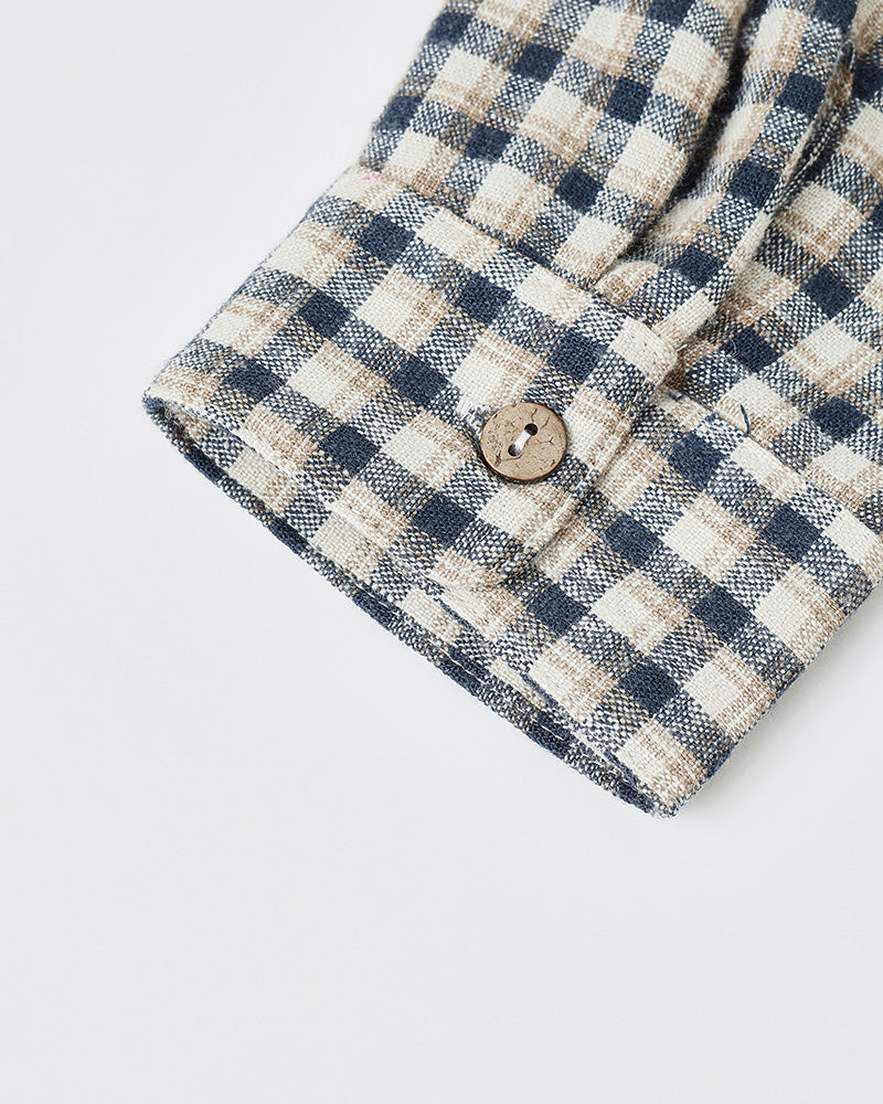 Close-up of a checkered shirt with a button on a light gray background