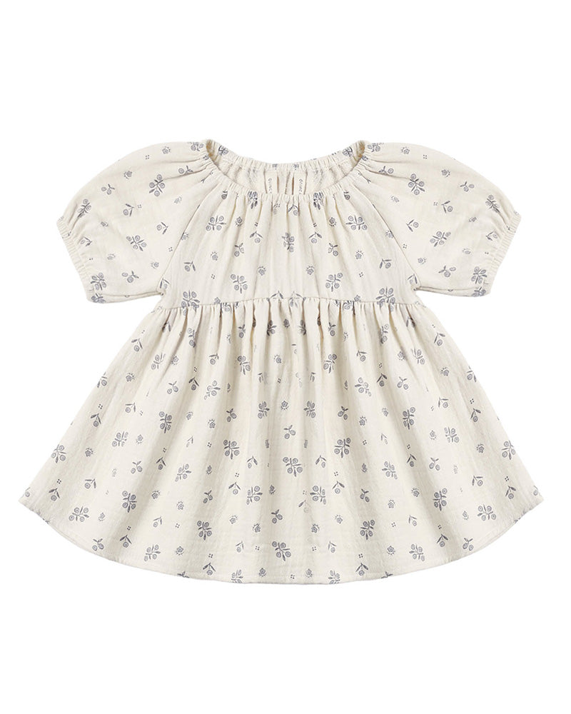 A baby girl's short-sleeve dress in cream cotton fabric with a delicate gray floral print, featuring a smocked bodice and puffed sleeves.