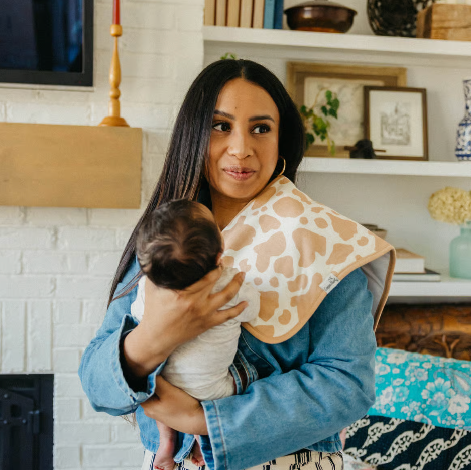 woman holding infant with cow print burp cloth over shoulder