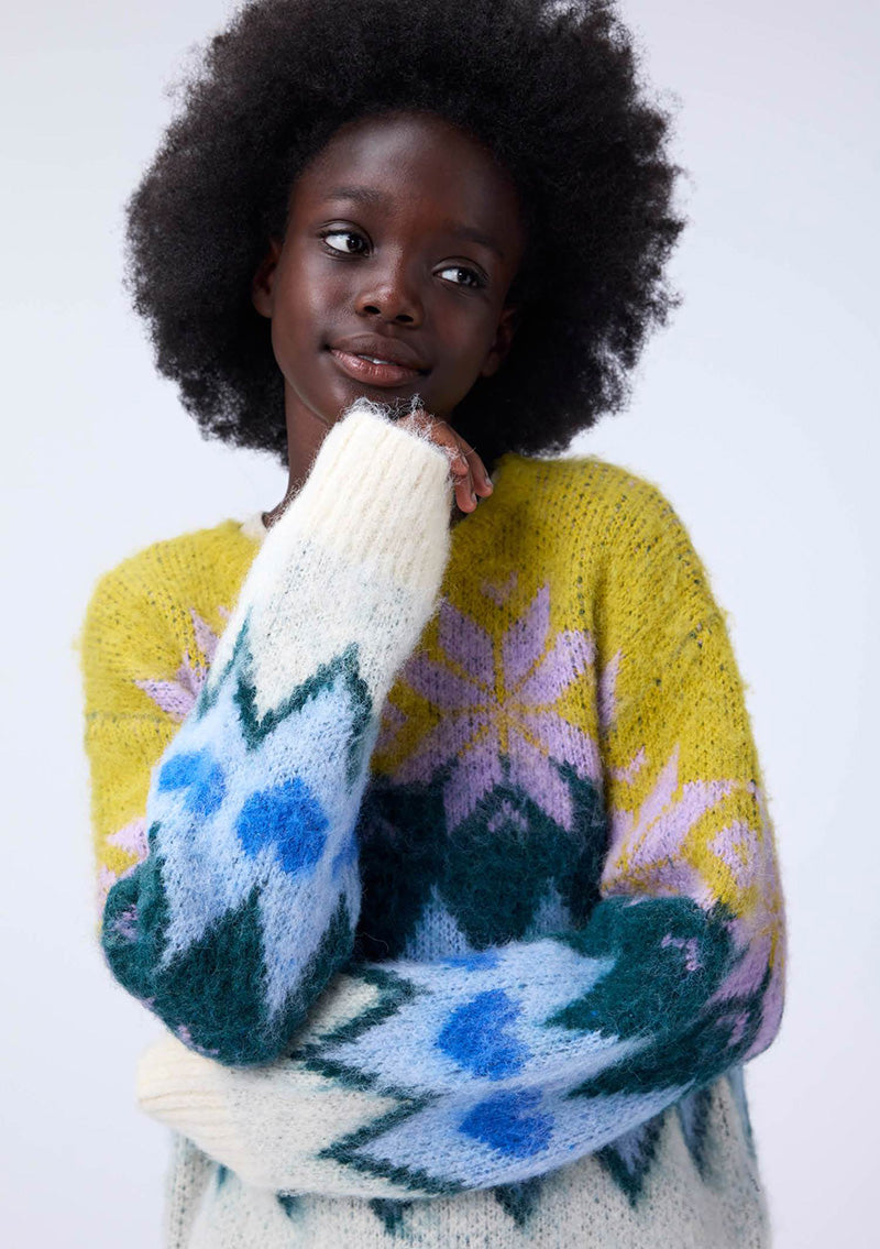 Person wearing a colorful sweater with abstract patterns on a white background