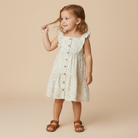 Young girl wearing a floral dress with ruffle sleeves on a beige background