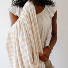 Woman holding a beige checkered blanket against a white background