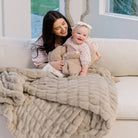 Woman and baby wrapped in a large light tan ruched blanket