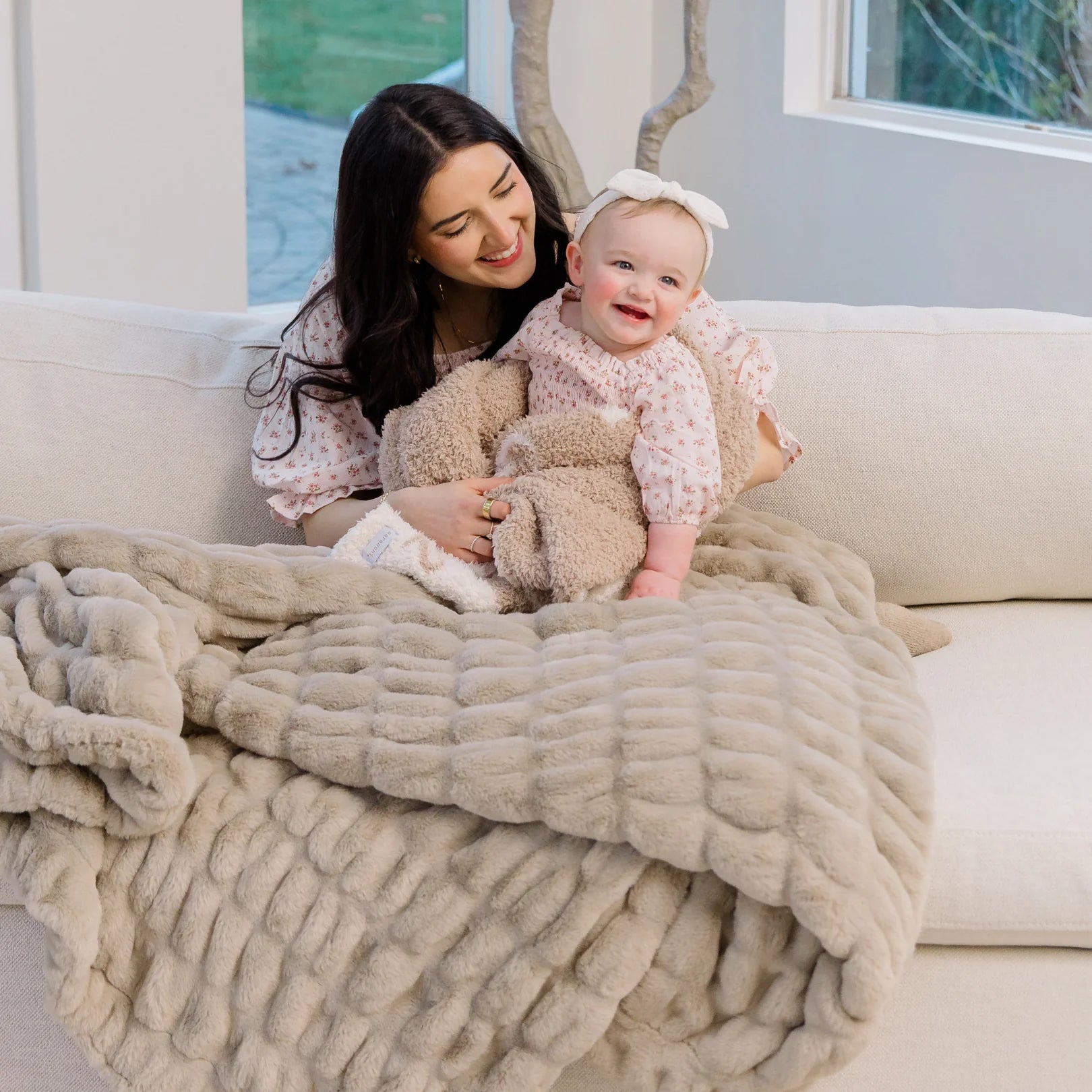 Woman and baby wrapped in a large light tan ruched blanket