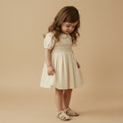 Young girl wearing a beige dress against a beige background