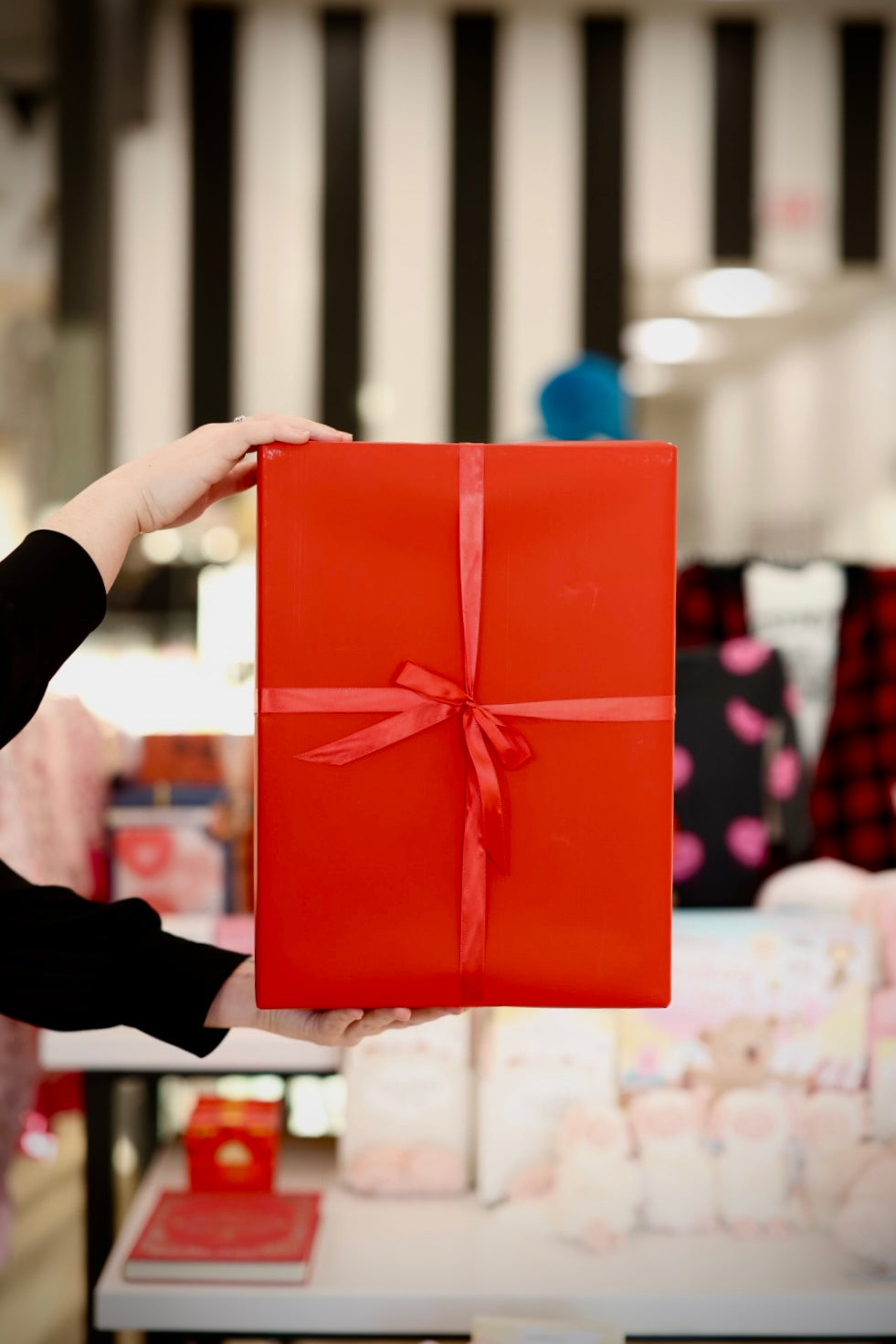 Person holding a red gift box with a bow in an indoor setting