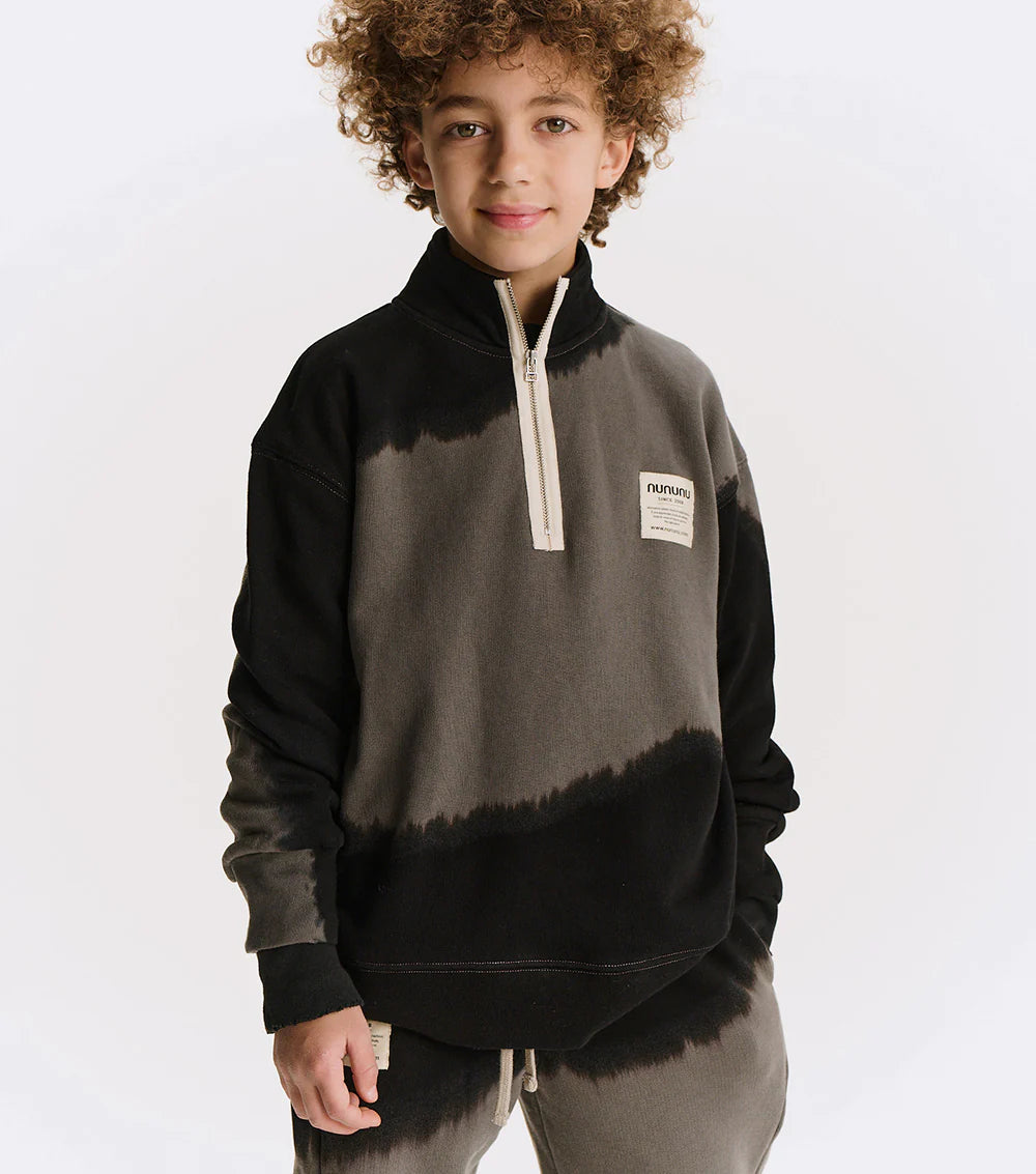 Child wearing a black and gray tie-dye pullover with a visible brand logo on a white background