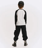 Person wearing a black and white long-sleeve shirt with black pants on a white background