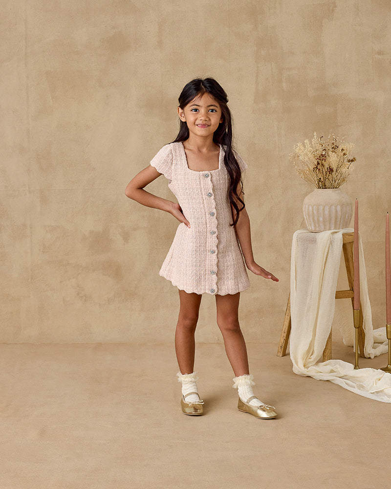 Young girl in a light dress standing against a beige background