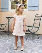 Young girl in a white dress standing on a stone patio with a building in the background