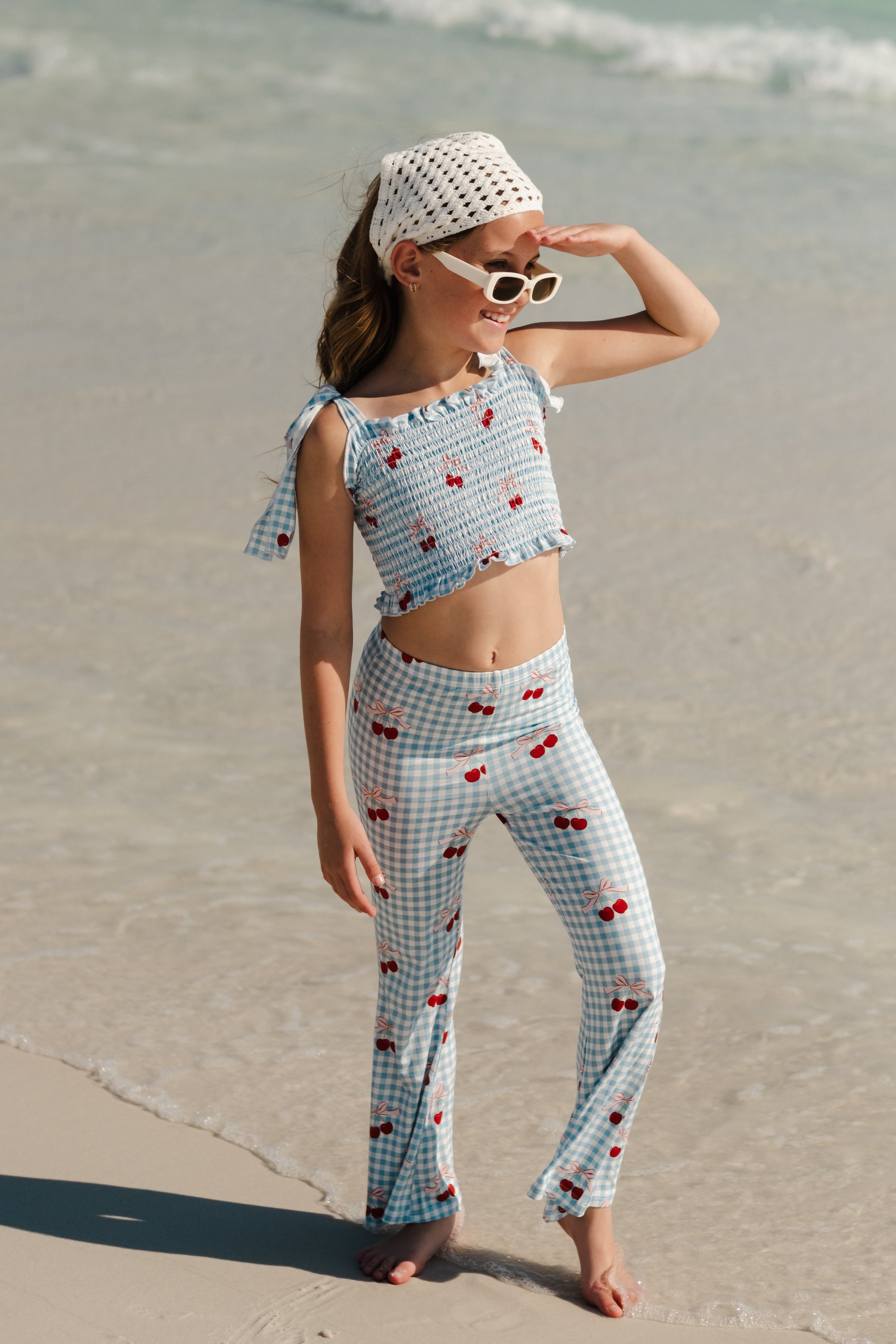 Girl in a two piece gingham set with a cherry pattern and tie sleeves