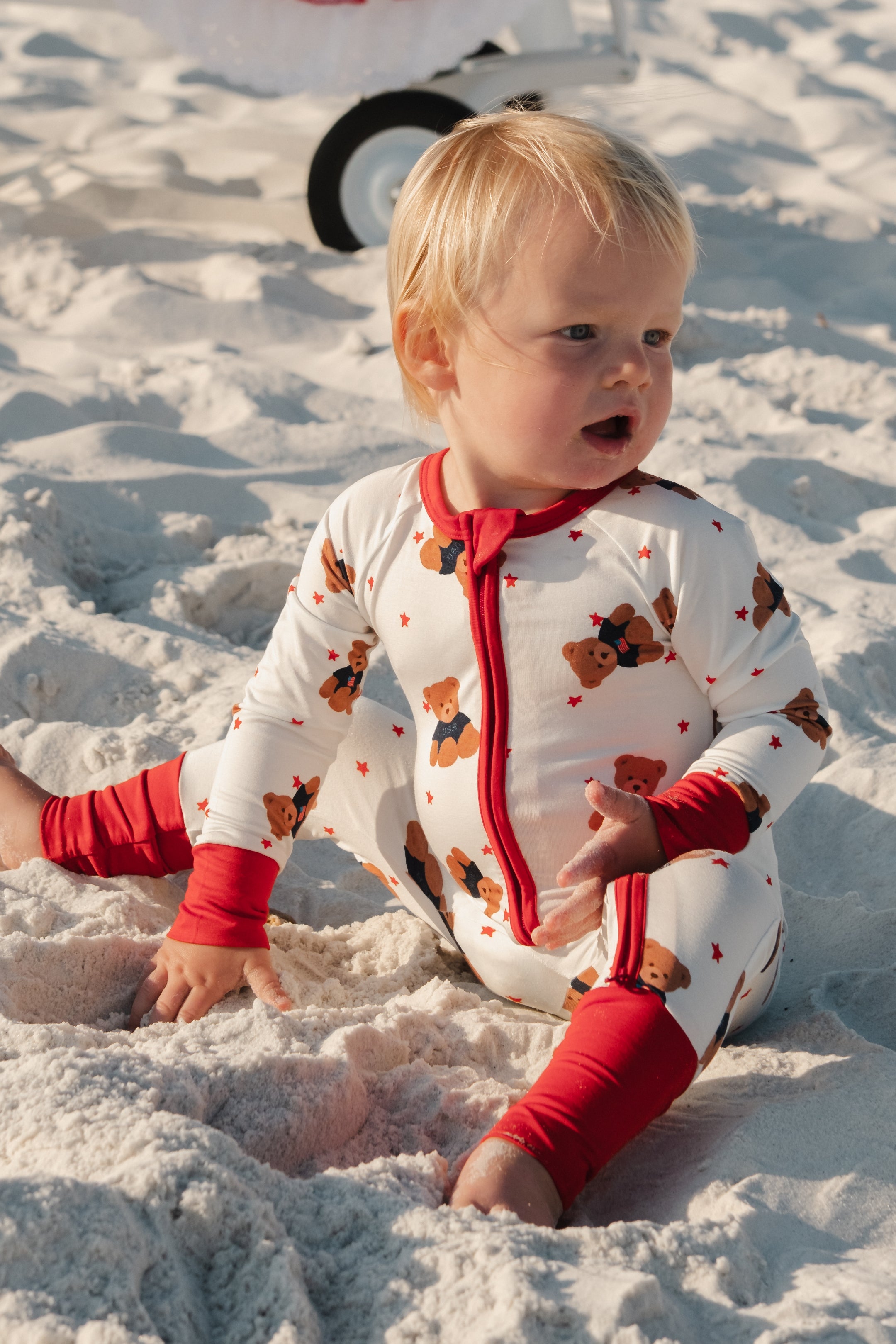 Baby onesie with a teddy bear and star print with a red trim