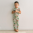 Child wearing a pajama set with a farm animal print against a plain background