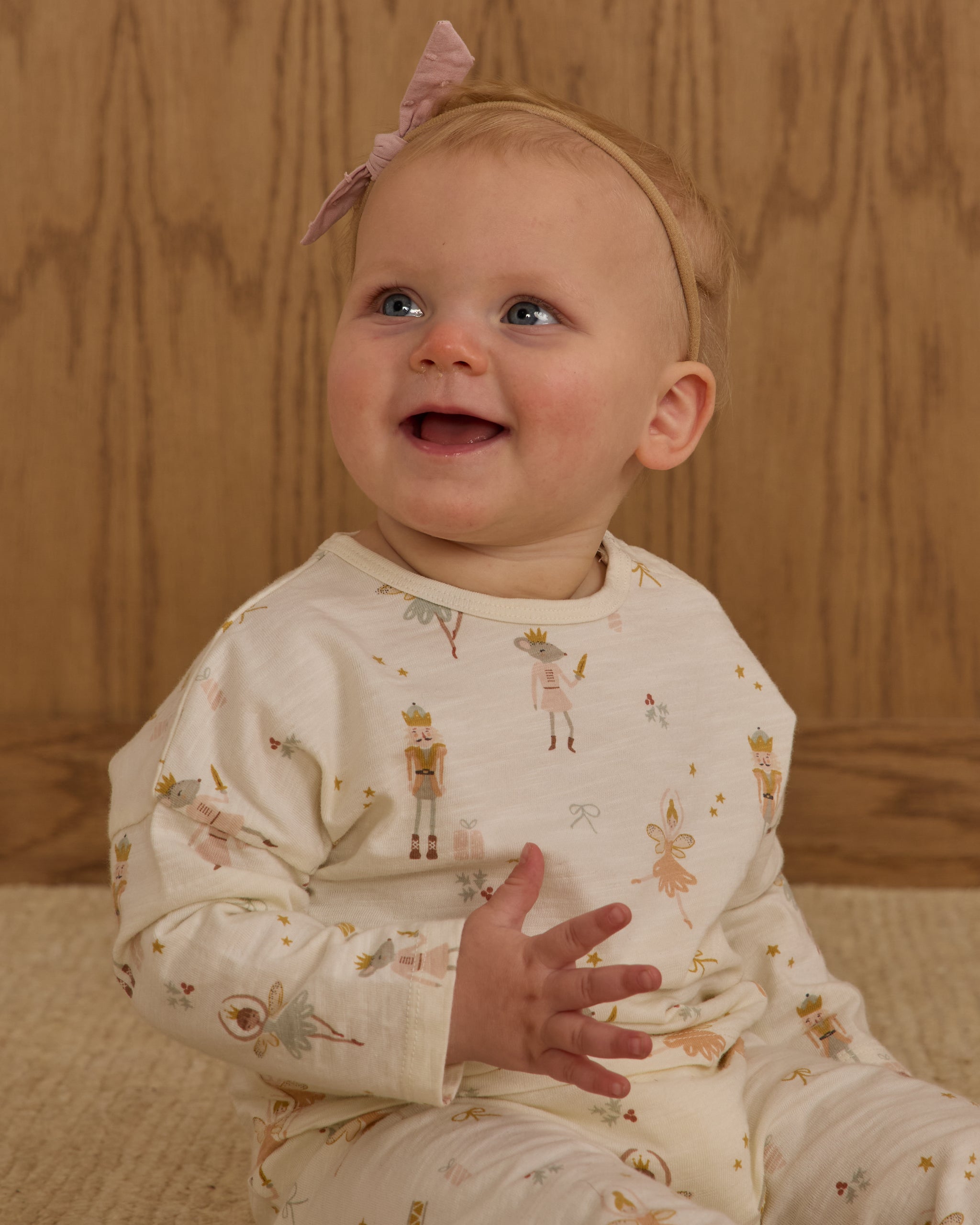 Baby wearing a holiday patterned outfit with a wooden background
