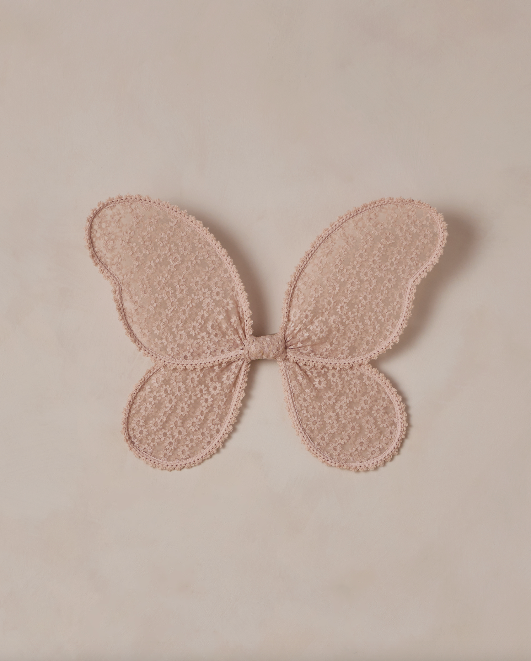 Pink floral embroidered butterfly wings against a beige background
