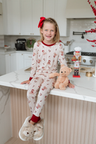 Young girl in pajamas sitting on a kitchen counter with a teddy bear