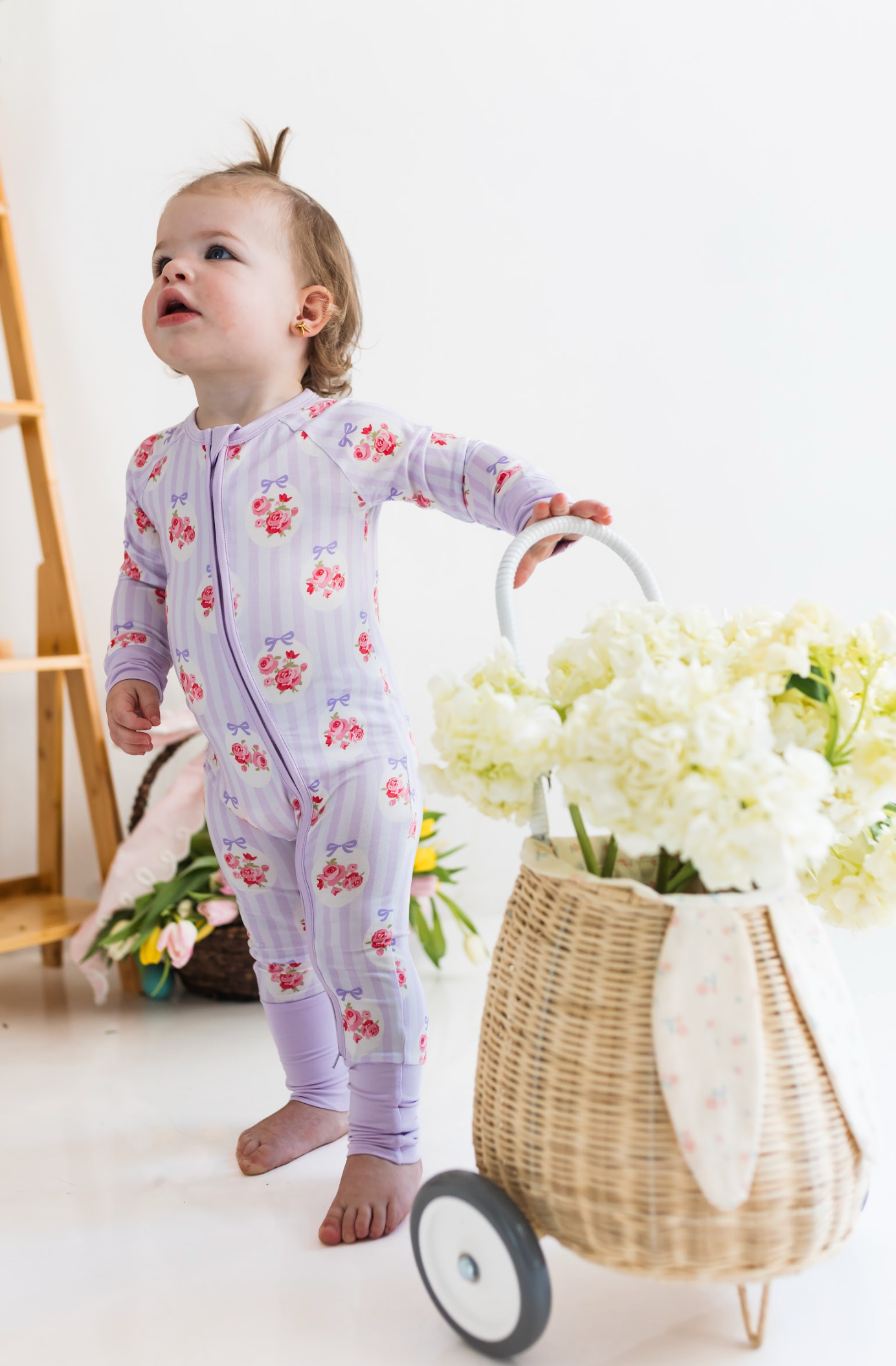 Child in floral pajamas with white and purple stripes. 