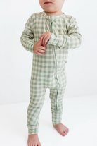 Child wearing a green checkered onesie on a white background