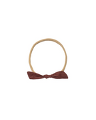 Beige headband with a maroon bow on a white background