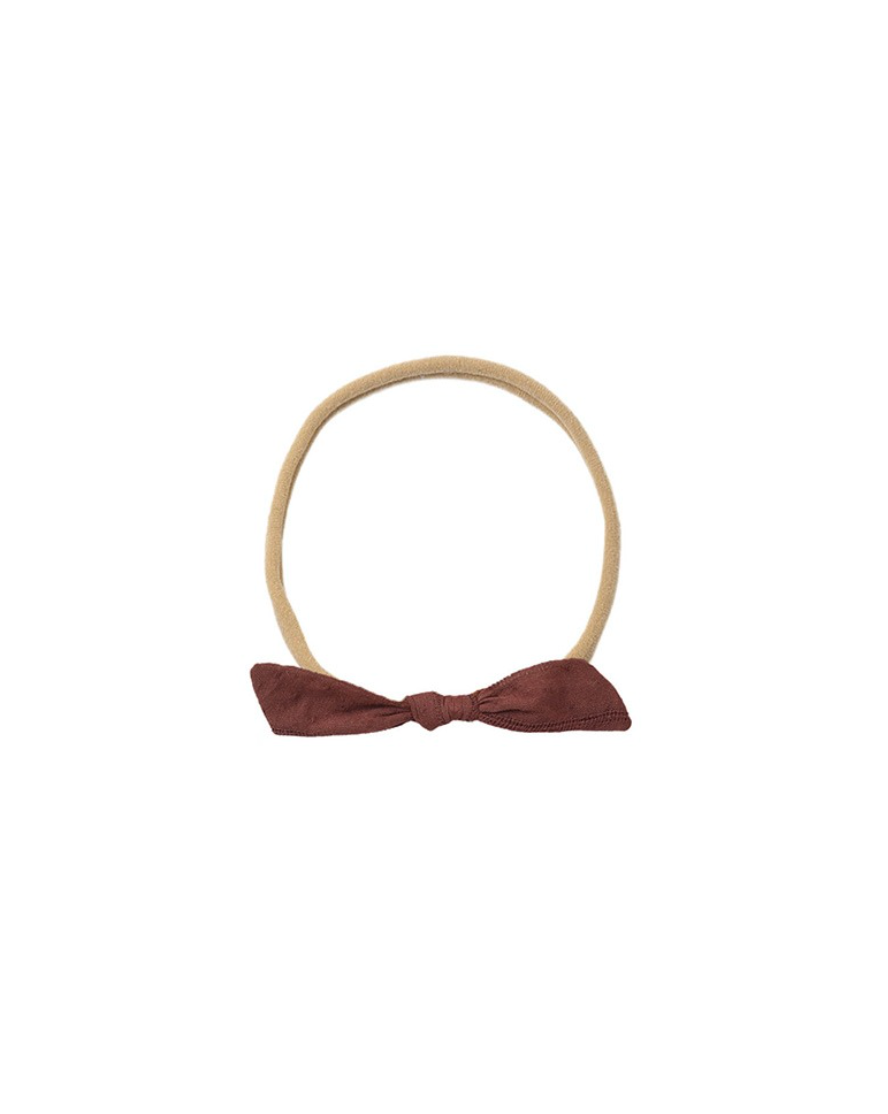 Beige headband with a maroon bow on a white background
