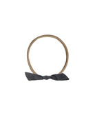 Tan elastic headband with a dark gray bow on a white background